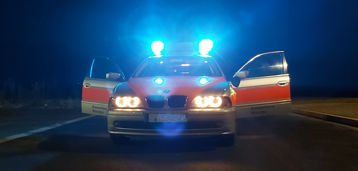 Helfer vor Ort Einsatzwagen mit Blaulicht.